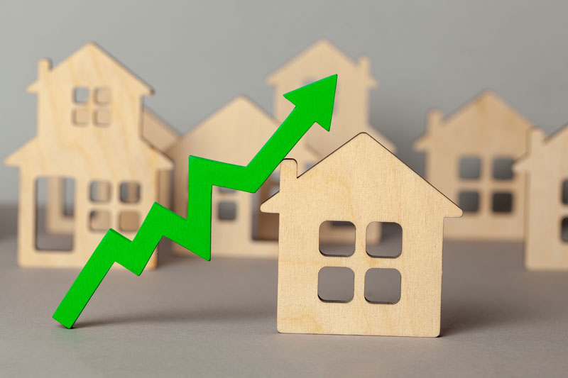 Wooden houses with a rising green arrow